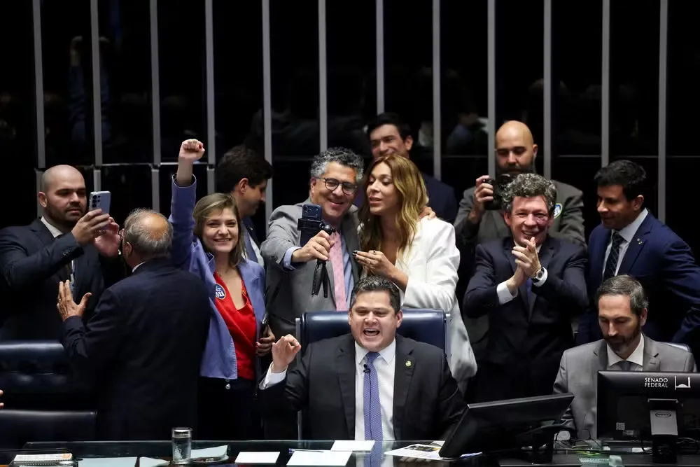 Colegas parlamentares comemoram enquanto o presidente do Senado Federal, Davi Alcolumbre, anuncia o resultado da votação a favor de uma emenda constitucional que reduz a jornada de trabalho no Brasil de seis para cinco dias, em Brasília, Brasil, 14 de out